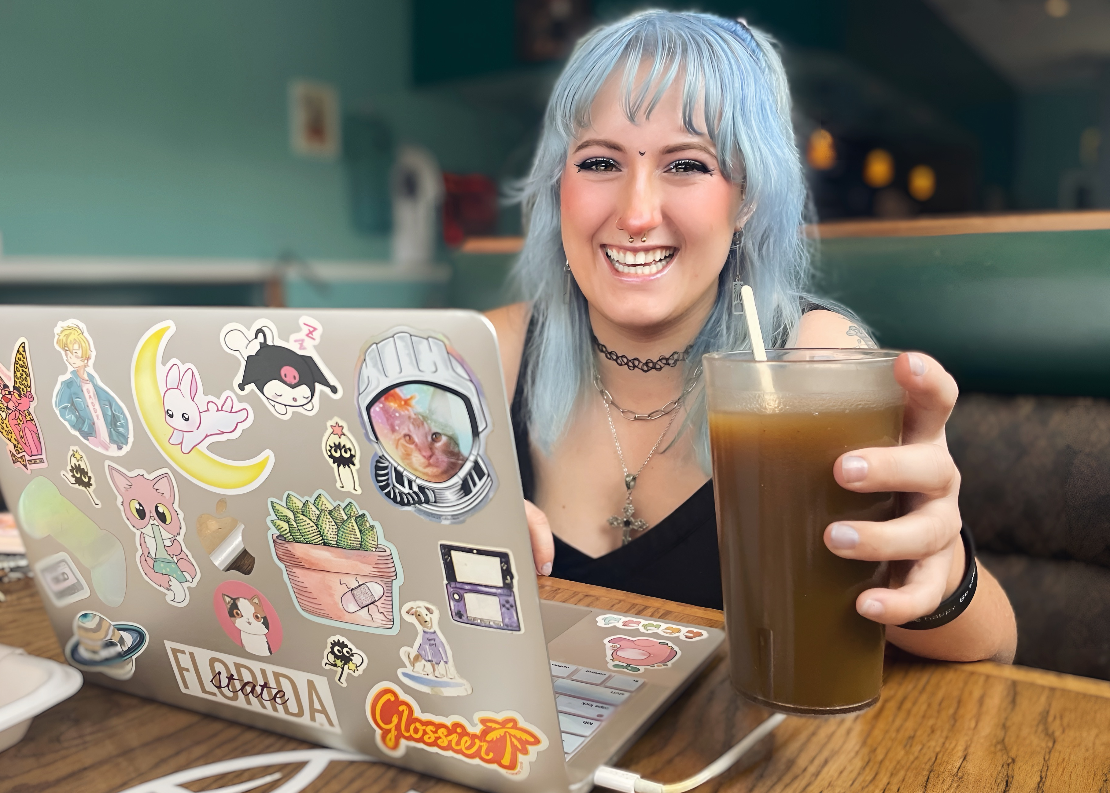 Erica, a regular at Midtown Kava Lounge enjoying a drink and working on her laptop smiling